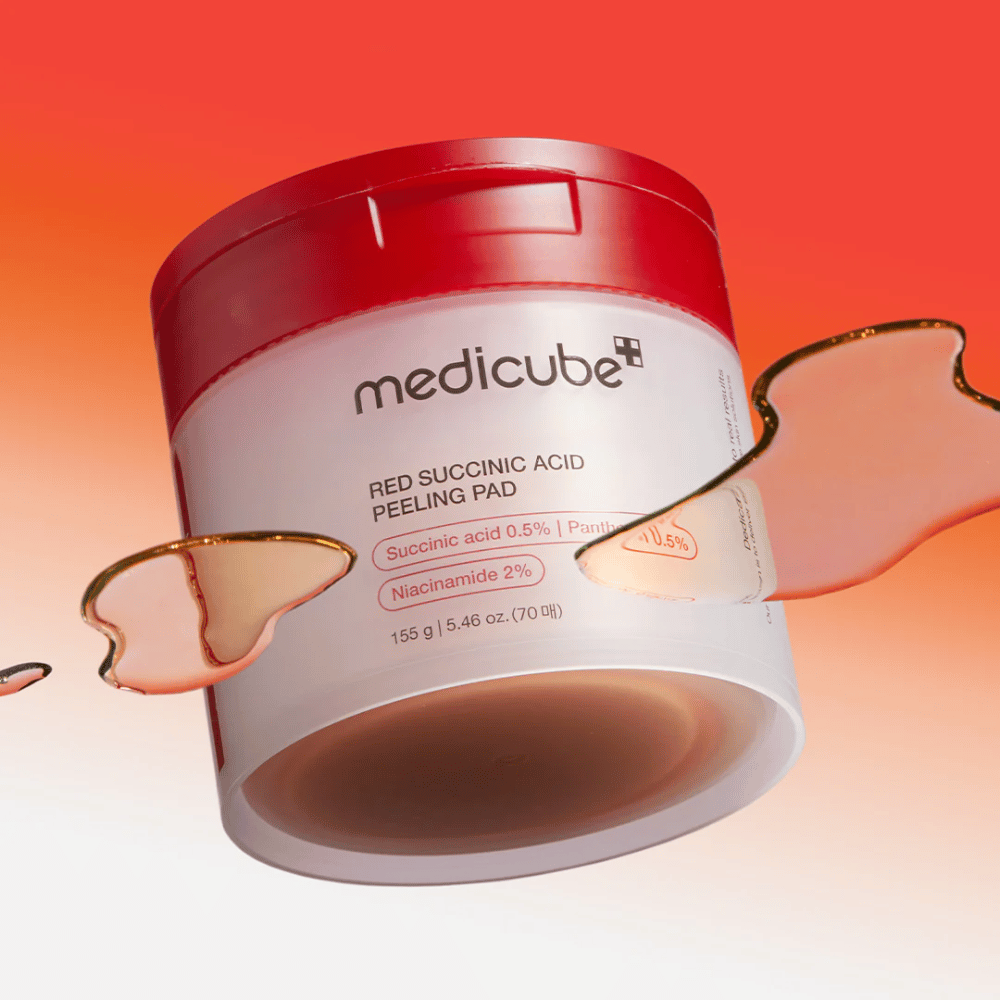 Medicube Red Succinic Acid Peeling Pad in einem weißen und roten Behälter, platziert vor einem roten und orangefarbenen Verlaufshintergrund. Das Produkt enthält Bernsteinsäure und Niacinamid für Peeling und Hautverbesserung. Flüssige Textur ist um den Behälter sichtbar.