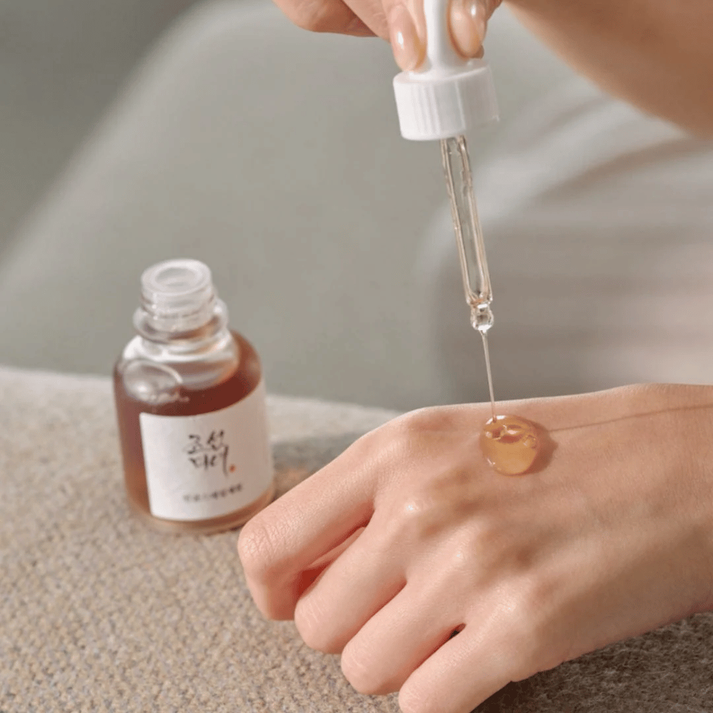 Pipette tropft Beauty of Joseon Revive Serum Ginseng + Schneckenschleim auf die Haut – koreanisches Serum für Elastizität und Feuchtigkeit.