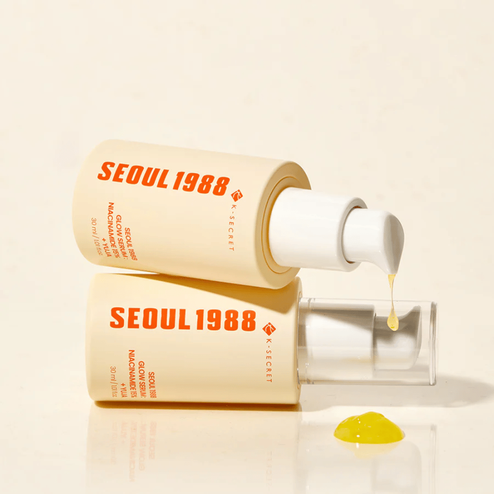 Zwei Flaschen Seoul 1988 Glow Serum liegend und stehend, mit gelbem Serum, das aus der Pumpe tropft.