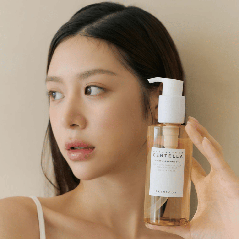 Eine Frau, die eine Flasche SKIN1004 Madagascar Centella Light Cleansing Oil 200 ml Gesichtsreinigung hochhält.