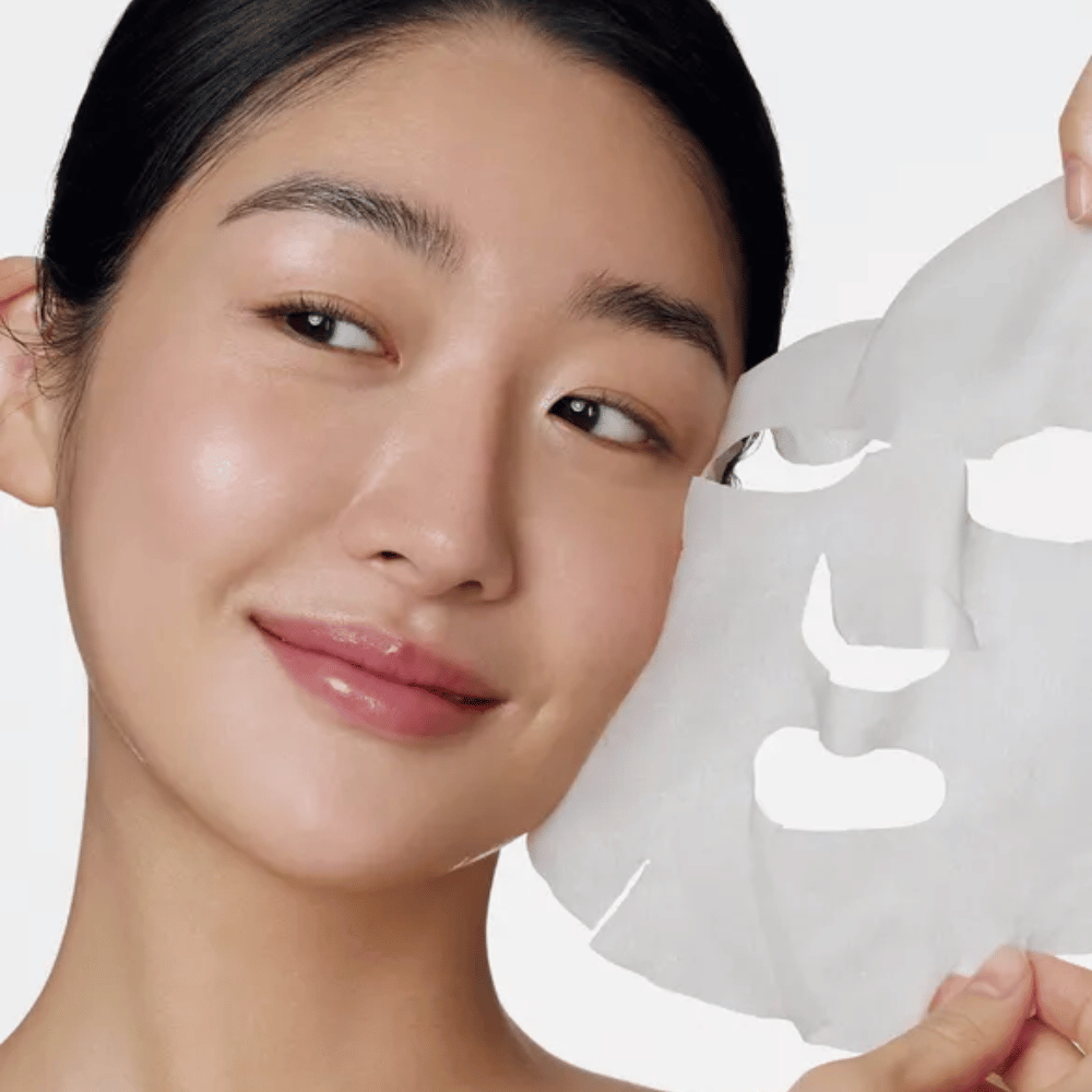 Das Bild zeigt eine Person, die eine Gesichtsmaske verwendet, speziell eine "Retinol Intense Daily Mask" von Some By Mi. Die Maske ist für die tägliche Anwendung konzipiert und enthält Retinol, um die Hauttextur zu verbessern, feine Linien zu reduzieren und einen gleichmäßigeren Hautton zu verleihen.