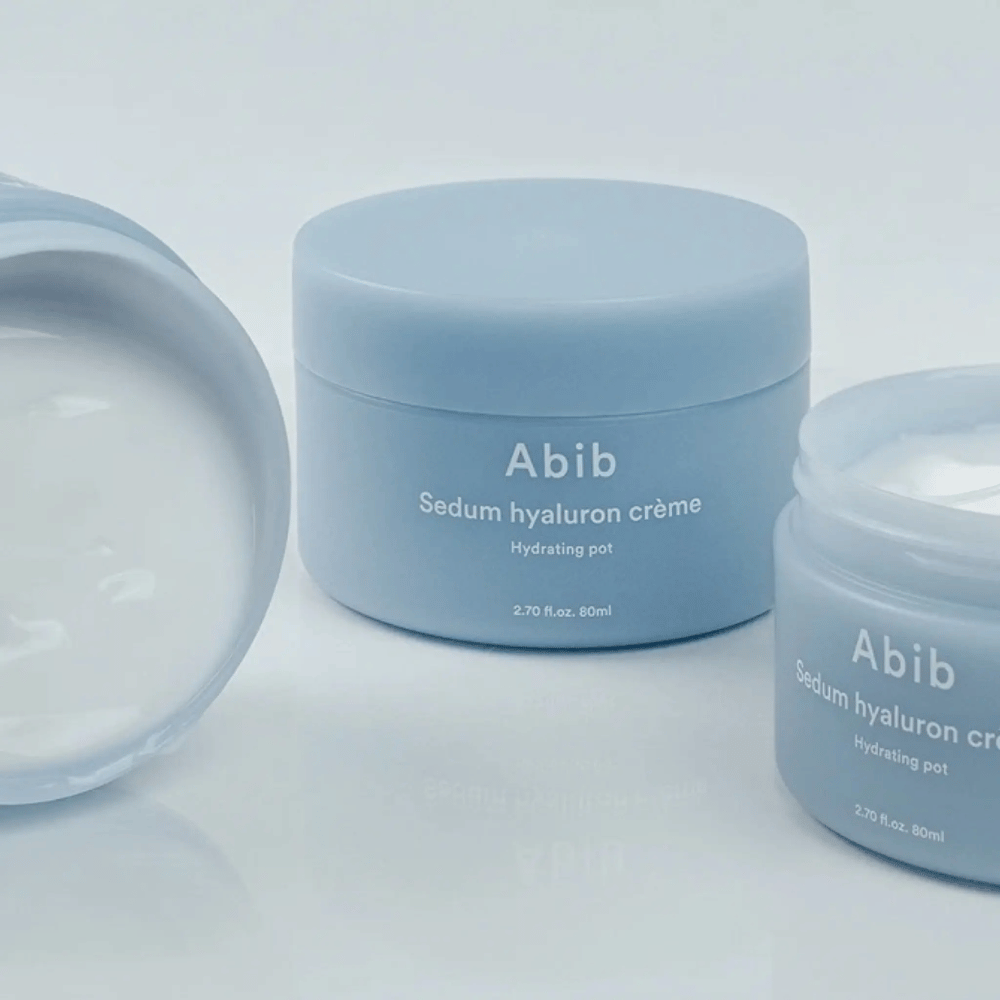 Drei Behälter von Abib Sedum Hyaluron Crème Hydrating Pot 80 ml im hellblauen minimalistischen Design, wobei ein offener Behälter die cremige weiße Konsistenz zeigt.