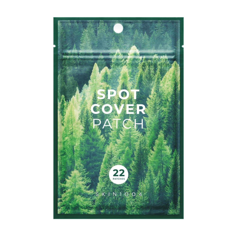 Verpackung mit "Spot Cover Patch", die 22 Pflaster enthält, gestaltet mit einem grünen Waldmotiv. Der Text "SPOT COVER PATCH" ist in Weiß auf der Vorderseite gedruckt, und ein Kreis markiert die Anzahl der Pflaster. Das Produkt stammt von der Marke SKIN1004.