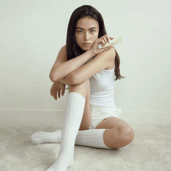 Lifestyle-Bild mit einem Model, das das Produkt in einer hellen und minimalistischen Umgebung hält. Das Bild vermittelt ein reines, natürliches und ruhiges Hautpflegegefühl, verbunden mit Glow- und Brightening-Effekt.