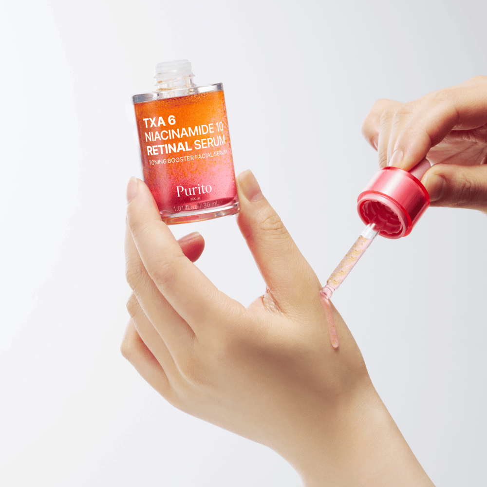 Hand trägt Purito TXA 6 Niacinamide 10 Retinal Serum auf. Leichte Formel mit aktiven Inhaltsstoffen für Strahlkraft, Elastizität und klarere Haut.