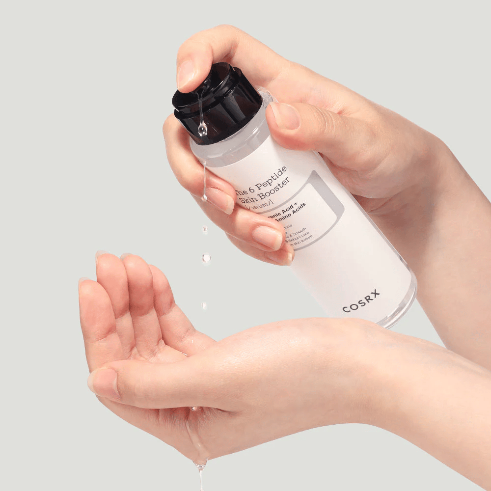 Hände, die ein Hautpflegeprodukt aus einer transparenten Flasche mit der Aufschrift "The Peptide Skin Booster" ausgießen.