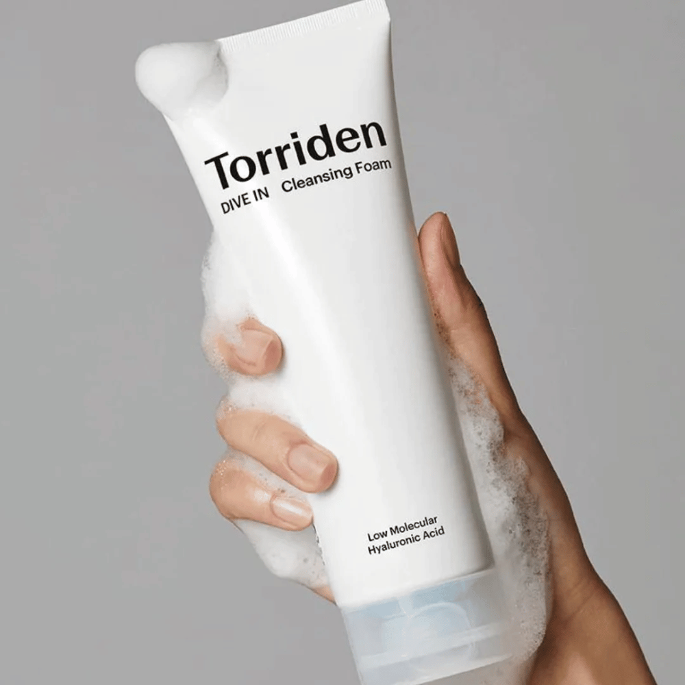 Eine Hand, die eine Tube pH-ausgeglichene Torriden DIVE-IN Low Molecular Hyaluronic Acid Cleansing Foam 150ml hält.