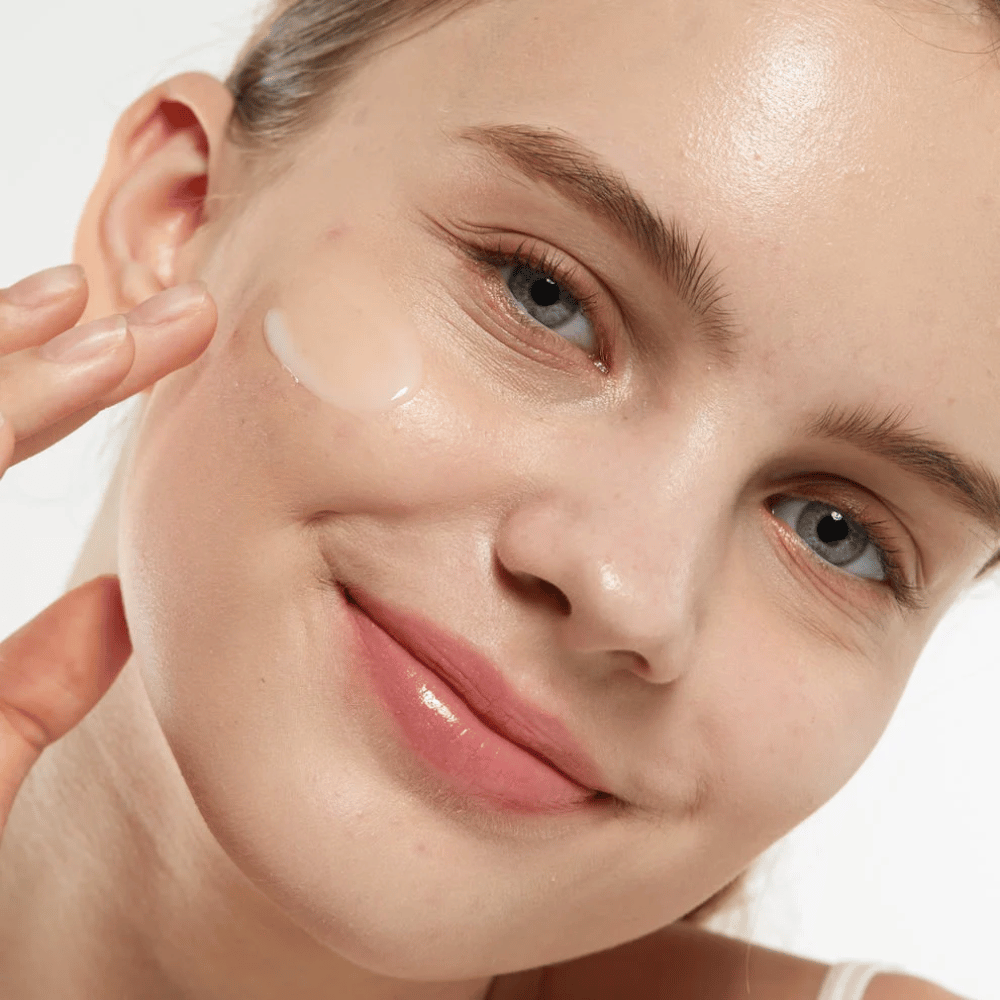 Modell, das Medicube Zero Pore Serum 2.0 auf die Wange aufträgt, ein porenverfeinerndes Serum, das eine gleichmäßigere Hautstruktur, Feuchtigkeit und einen natürlichen Glanz bietet.