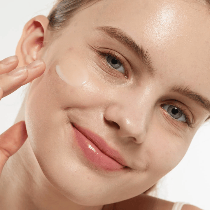 Modell, das Medicube Zero Pore Serum 2.0 auf die Wange aufträgt, ein porenverfeinerndes Serum, das eine gleichmäßigere Hautstruktur, Feuchtigkeit und einen natürlichen Glanz bietet.