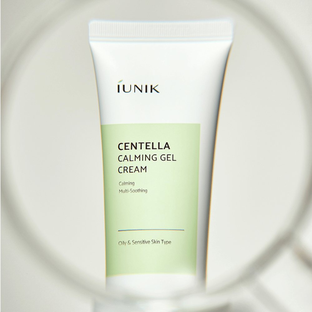 Eine Tube iUNIK Centella Calming Gel Cream mit weißem und hellgrünem Design steht aufrecht, gesehen durch einen runden, lupenähnlichen Rahmen.