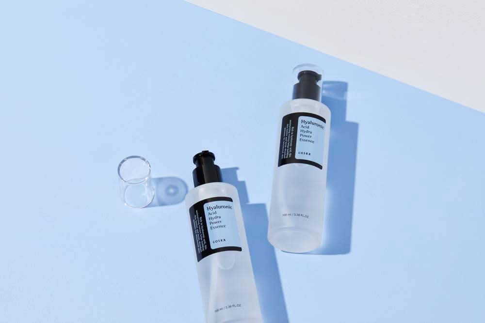 COSRX:s Hyaluronic Acid Hydra Power Essence 100ml bietet feuchtigkeitsspendende Vorteile auf blauer Oberfläche.