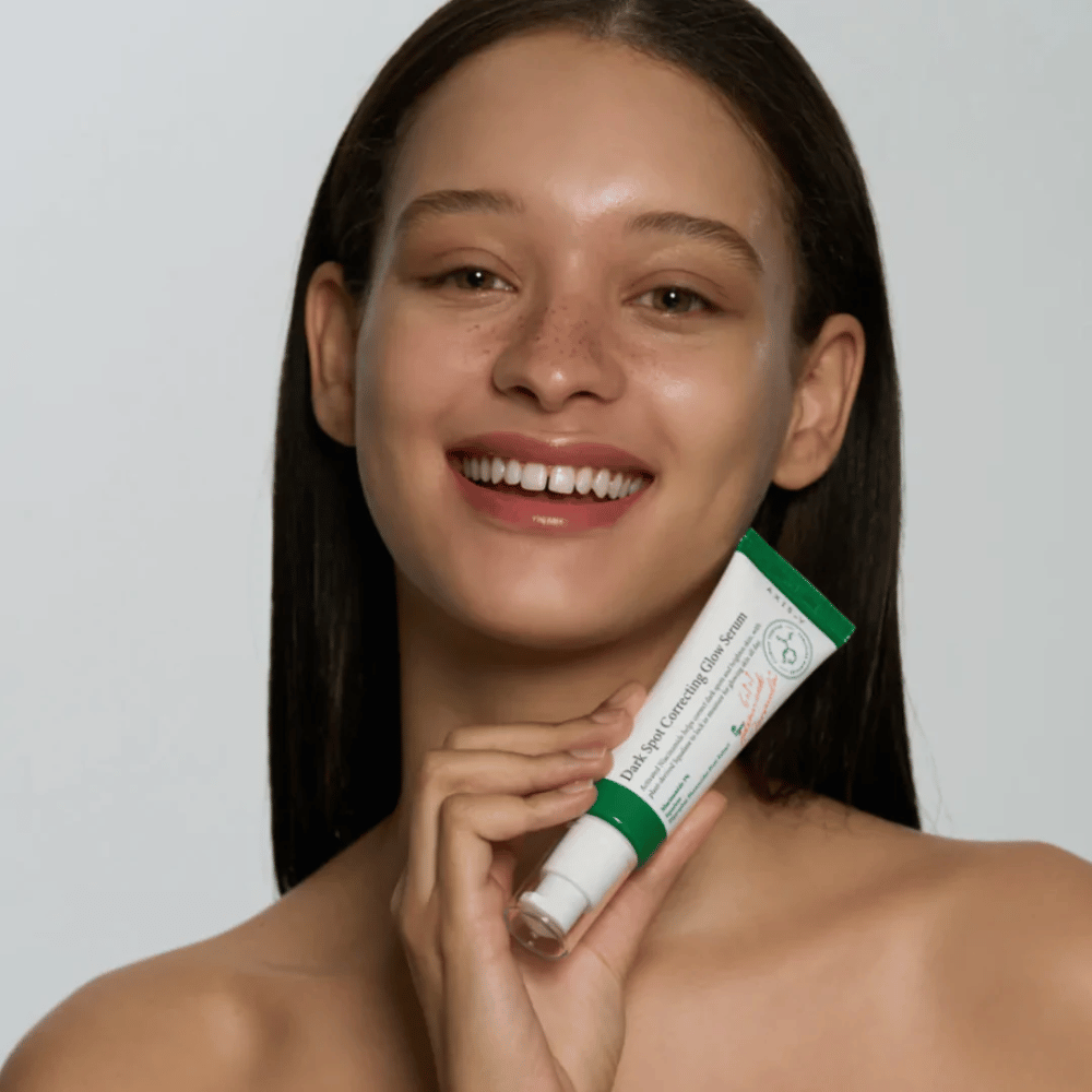 Eine junge Frau hält eine Tube mit AXIS - Y Dark Spot Correcting Glow Serum 50ml.