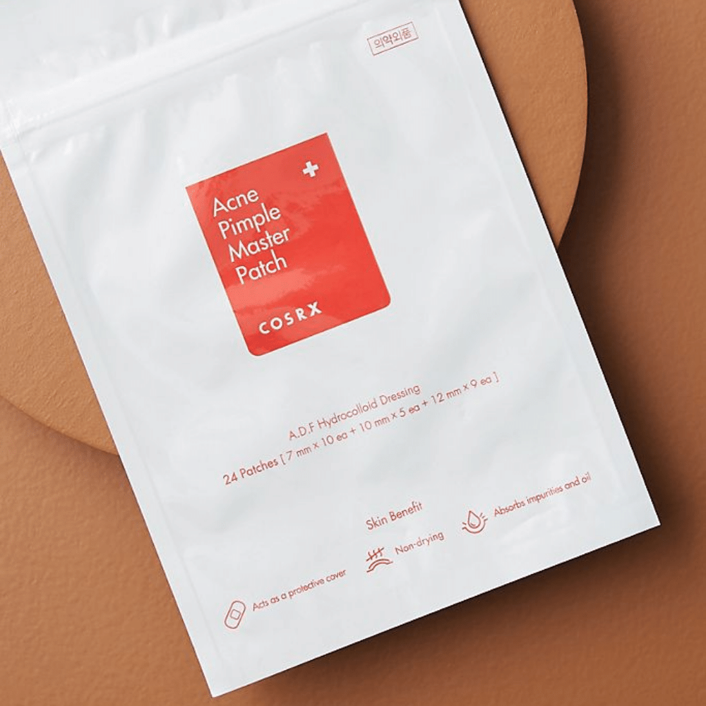Ein Paket COSRX Acne Pimple Master Patch (1 Packung x 24 Pflaster) auf einem braunen Hintergrund, mit Hydrocolloid-Technologie zur Behandlung von Akne und Pickeln.