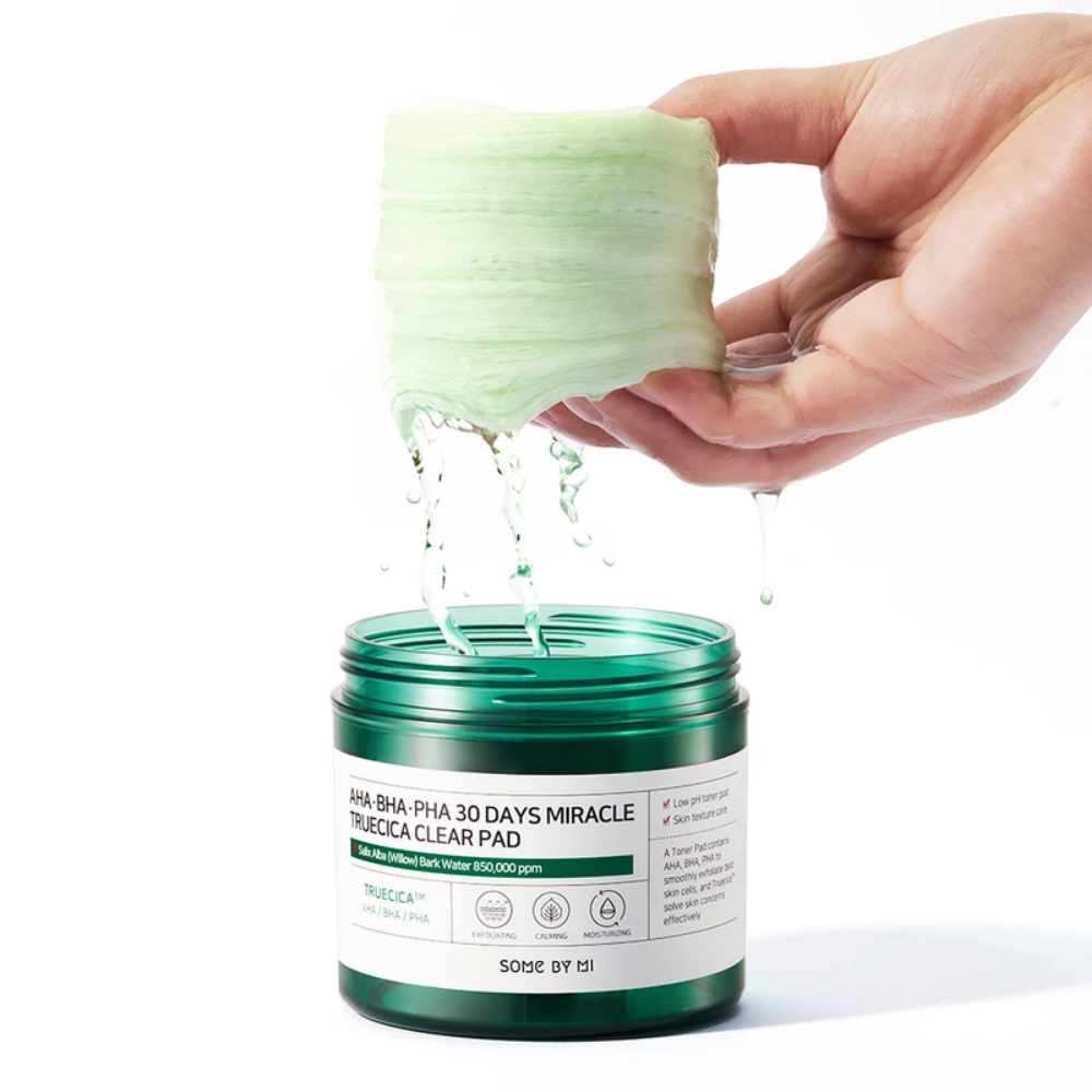 Eine Hand gießt eine grüne Flüssigkeit in ein Glas für SOME BY MI:s AHA, BHA, PHA 30 Days Miracle Truecica Clear Pad 70 St Akneausbruchsbehandlung.