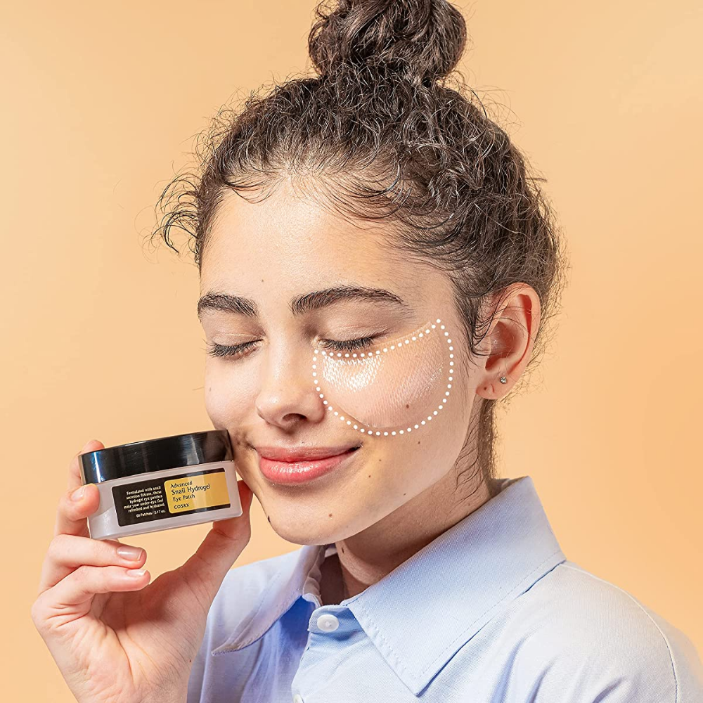 Eine Frau, die ein Glas COSRX Advanced Snail Hydrogel Eye Patch 60 Stk. Gesichtscreme hält.