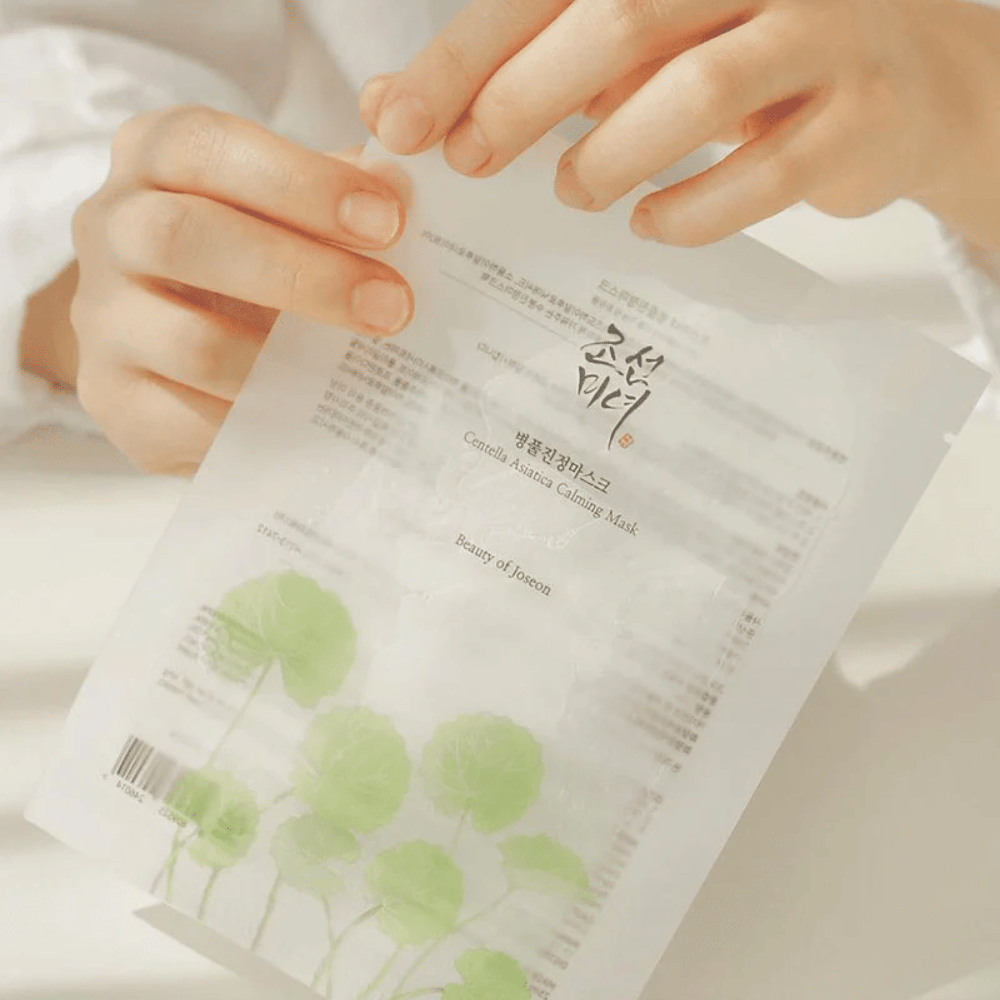Eine Person, die ein Blatt Papier mit einem Beauty of Joseon Centella Asiatica Calming Mask 1 Stk. darauf hält.