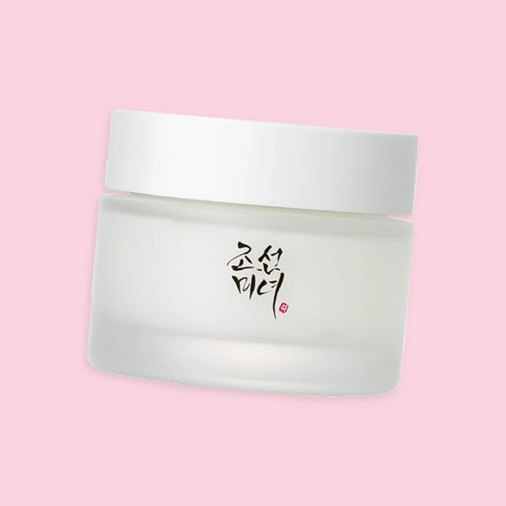 En burk med Beauty of Joseon Dynasty Cream 50g med koreansk ginseng och orkidéextrakt på en rosa bakgrund.