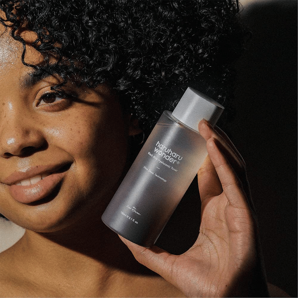 Eine Frau, die eine Flasche Haruharu Wonder Black Rice Hyaluronic Toner Original 150ml hochhält.