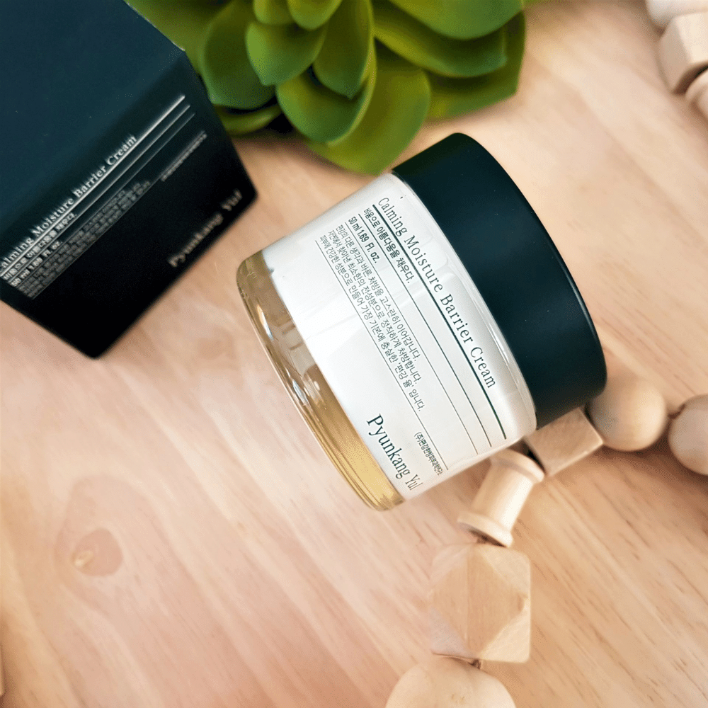Ein Glas Pyunkang Yul Calming Moisture Barrier Cream 50ml, das auf einem Holztisch steht.